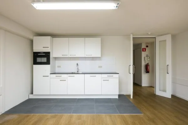 Moderne witte keuken met ingebouwde oven en grijze tegels in een appartement aan de Prins Hendrikkade.